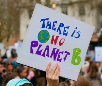 Person holding a sign at a protest that reads "There is no planet B" with a drawing of Earth.