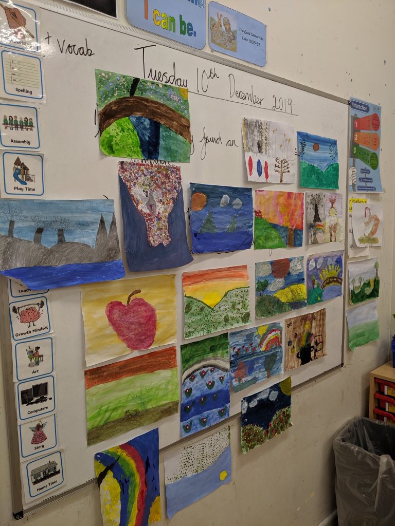 A whiteboard displays children's colourful paintings, with a date written above: Tuesday 10th December 2019.